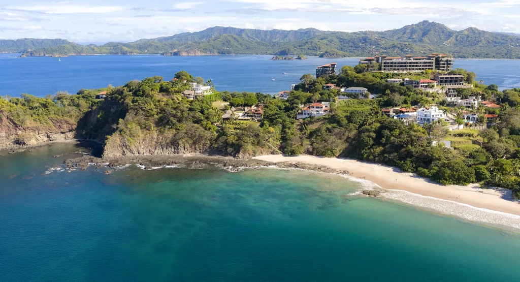 Aerial view of the North Ridge of Playa Flamingo — white-sand cove, turquoise water, and the ridge-top residences of 360 Splendor.